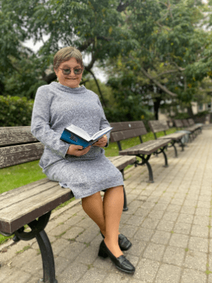 Skolotāja Māra Ozola ar grāmatu parkā